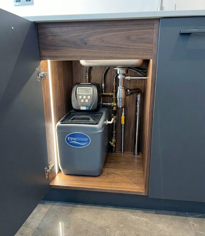 Kabinetli bir su yumuşatma cihazının mutfak dolabı veya tesisat odasındaki duruşu