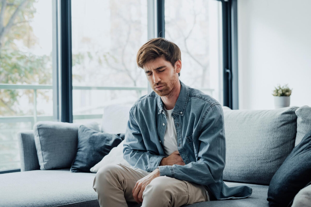Person sitting, holding stomach in discomfort.